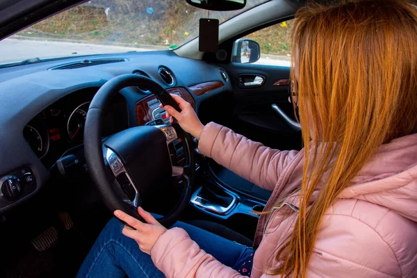 Bir arabanın arkasında oturan kız araba sürmeyi öğreniyor.