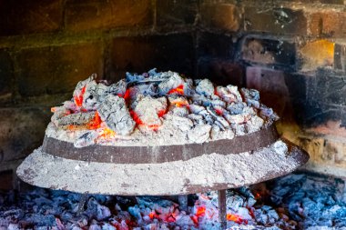 Kese, metal kapak kül ve yemek pişirmek için kullanılan kömürlerle kaplı.