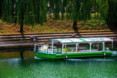 Ljubljanica nehrine bakan insanlar, 2019.07.26 Avrupa ülkesinin başkenti Ljubljana 'da önlerinden tekne geçerken,