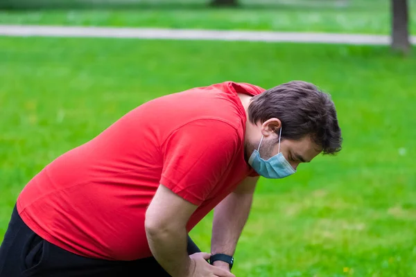 Şişman adam karantinada kilo vermek için ameliyat maskesini takıyor.