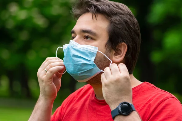 Man with quarantine hairstyle wearing surgical face mask outside to prevent hisself from corona virus