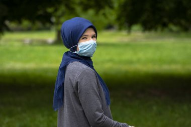 Cerrahi maske takan modern Müslüman kadın Corona virüsüyle savaşıyor.