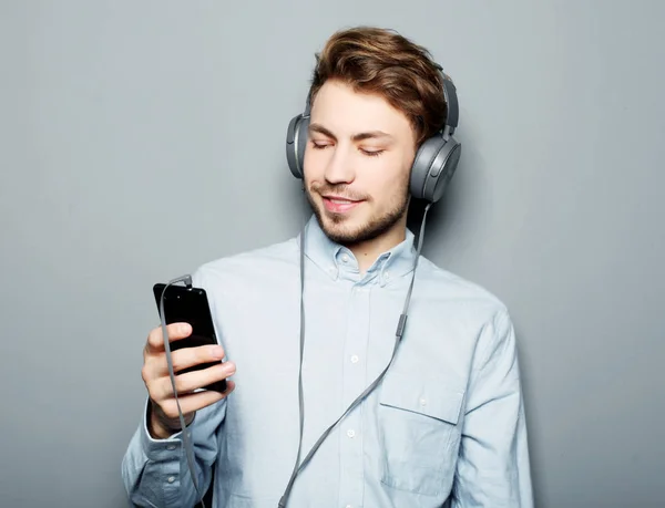 Ung man med hörlurar och mobiltelefon — Stockfoto