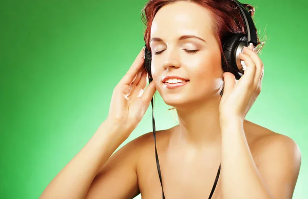 Молодая счастливая женщина слушает музыку с головными уборами Стоковое Фото