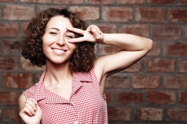 Aantrekkelijke krullend vrouw op bakstenen muur — Stockfoto