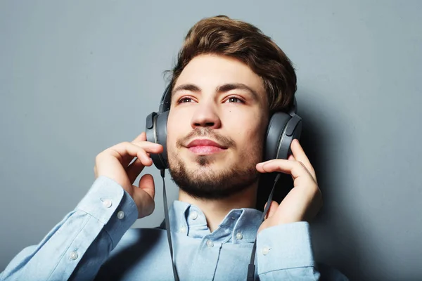 행복 한 세련 된 젊은이 wh 웃는 그의 헤드폰 광고를 조정 — 스톡 사진