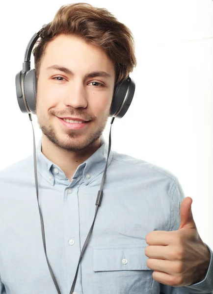 Bonito jovem vestindo fones de ouvido e ouvindo música . — Fotografia de Stock
