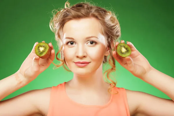 Charming young woman holding fresh juicy kiwi and smiles. — Stock Photo, Image