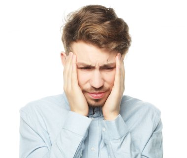 Genç iş adamı kafasına dokunuyor ve gözlerini kapalı tutuyor.