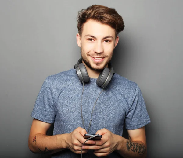 Guapo joven con auriculares en el cuello y sonriendo wh — Foto de Stock