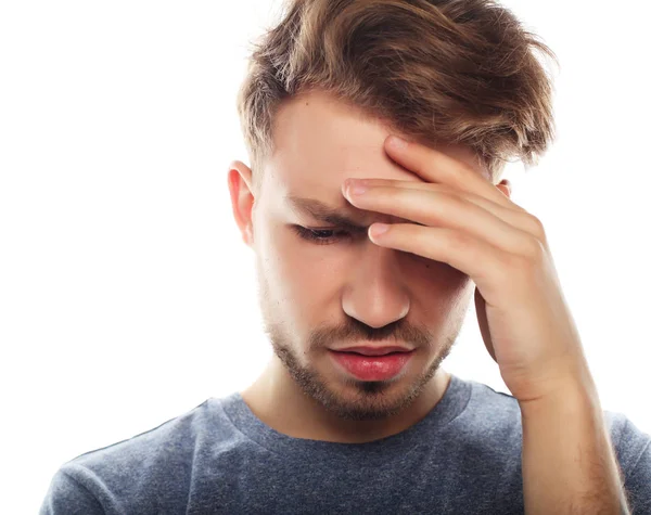 Genç iş adamı kafasına dokunuyor ve gözlerini kapalı tutuyor.