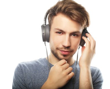 Kulaklıklar giyen ve ayakta gülümseyen yakışıklı delikanlı