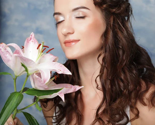 Schoonheid gezicht van de jonge vrouw met roze lelie — Stockfoto