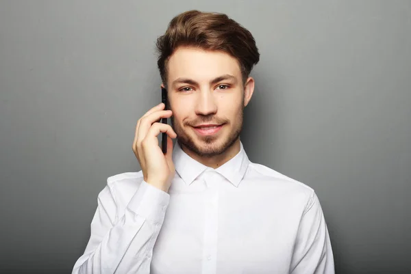 Happy obchodní muž volání s jeho smartphone proti šedé bac — Stock fotografie