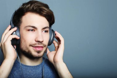 Kulaklık takıp müzik dinleyen yakışıklı bir genç..