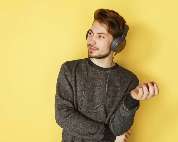 Bello uomo leccare per musica su sfondo giallo — Foto Stock