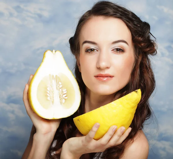 Meisje houdt grote citrusvruchten - pamelo, boven de hemelachtergrond — Stockfoto