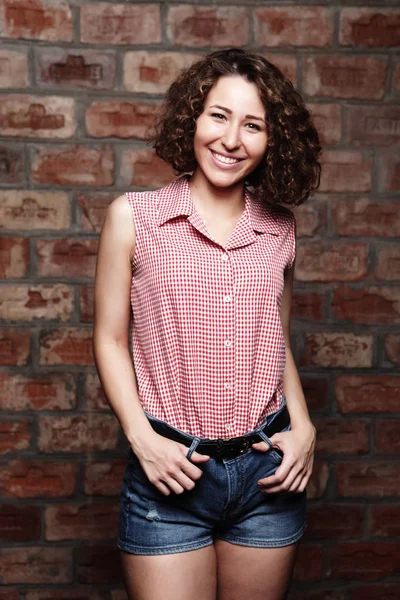 Attractive curly woman on brick wall — Stock Photo, Image