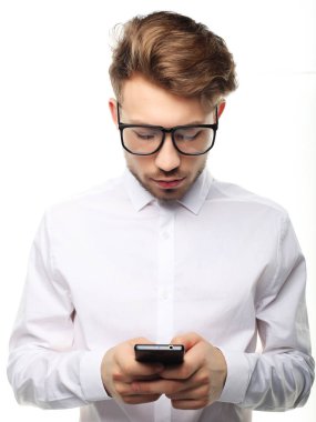 Genç, neşeli iş adamı cep telefonuna mesaj yazıyor.