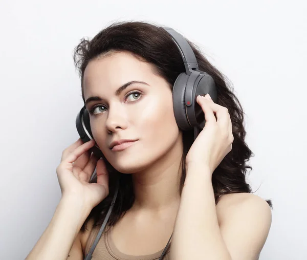Životní styl a lidé koncept: mladá žena s sluchátka liste — Stock fotografie