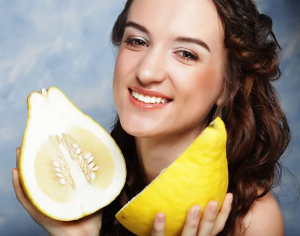 Meisje houdt grote citrusvruchten - pamelo, boven de hemelachtergrond — Stockfoto