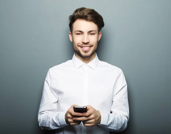 Joven hombre de negocios alegre escribiendo sms en su teléfono móvil — Foto de Stock