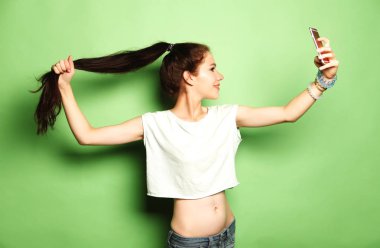 Sevimli kadın selfie fotoğraf smartphone üzerinde yeşil arka yapma.