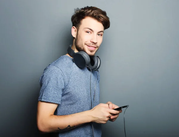 Schöner junger Mann mit Kopfhörern auf dem Hals und einem Lächeln wh — Stockfoto