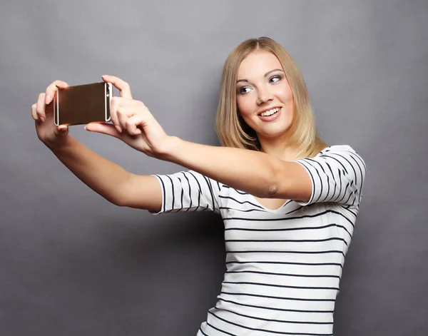 Donna elegante fare foto selfie su smartphone sopra zaino grigio Immagini Stock Royalty Free