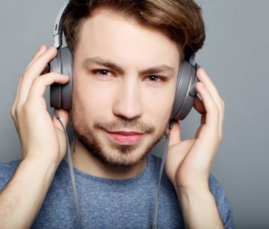 Mutlu genç şık adam WH gülümseyen onun kulaklık reklamı ayarlama