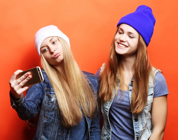 Duas adolescentes amigas em roupa hipster fazem selfie em um pho — Fotografia de Stock