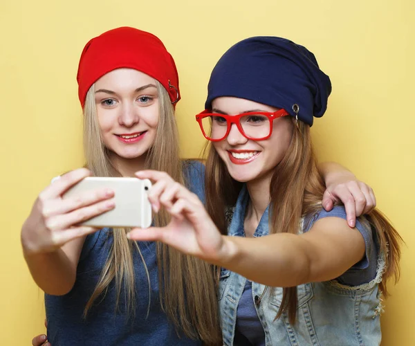 Счастливые девушки со смартфоном на жёлтом фоне. Счастливый я — стоковое фото