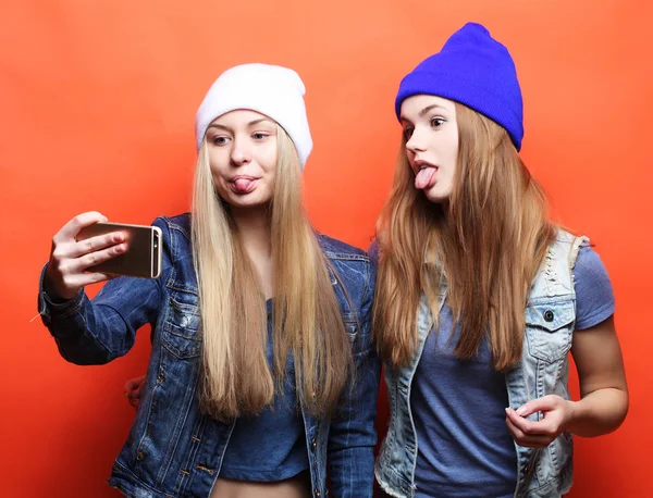 Duas adolescentes amigas em roupa hipster fazem selfie em um pho — Fotografia de Stock