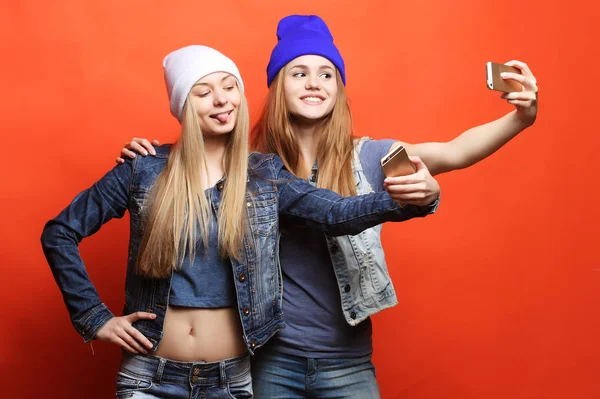 Dos amigas adolescentes en traje hipster hacen selfie en un pho —  Fotos de Stock