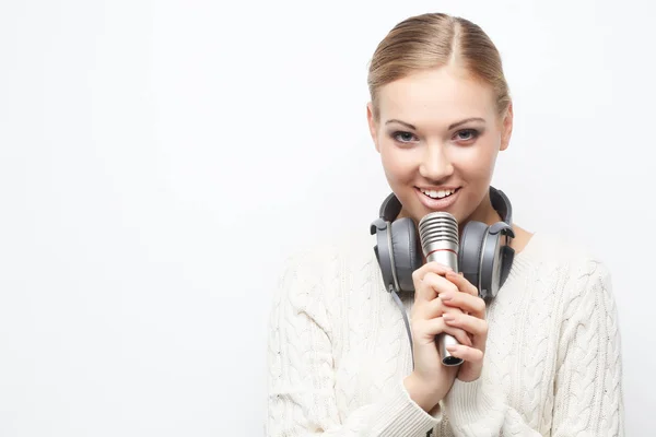 Młoda kobieta śpiewa do mikrofonu ze słuchawkami w studio na — Zdjęcie stockowe