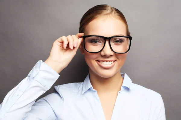 Boldog mosolygó fiatal üzletasszony szemüveget, mint szürke háttérben — Stock Fotó