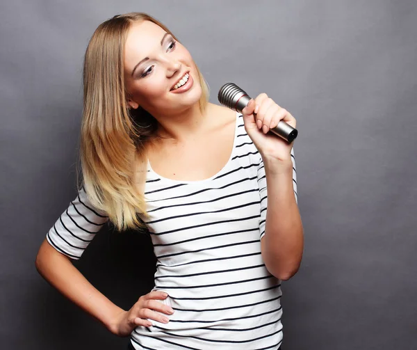 Skönhet kvinna klädd i t-shirt med mikrofon över grå bakgr — Stockfoto