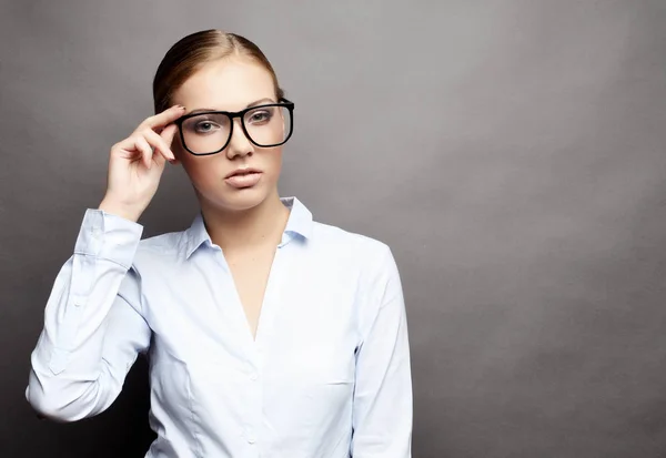 Geschäftsfrau mit Brille vor grauem Hintergrund — Stockfoto