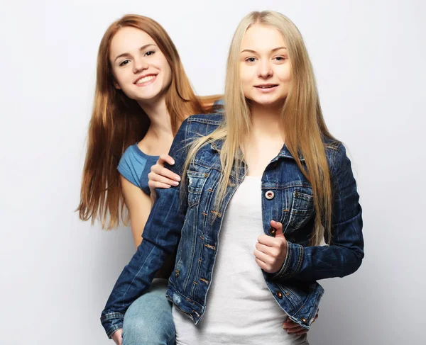 Twee jonge meisje vrienden staan samen en hebben plezier. — Stockfoto