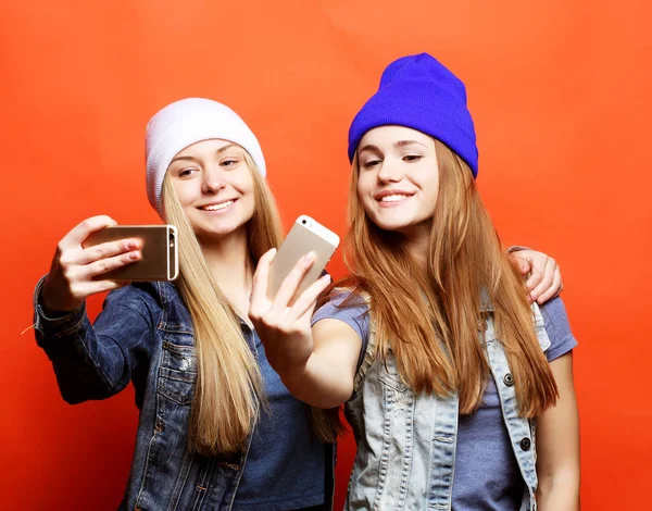 Due amiche adolescenti in abito hipster fanno selfie su un pho — Foto Stock