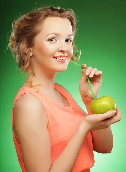 Mujer sonriente con manzana y cóctel de pajitas, sobre fondo verde —  Fotos de Stock