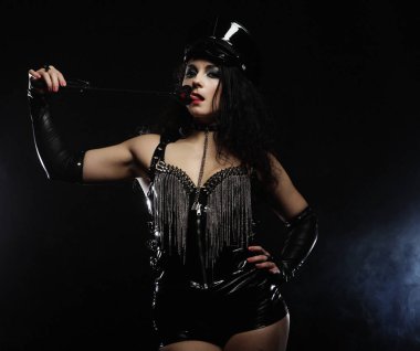 Seksi esmer kadın metresi kırbaç, üzerinde koyu backgrouynd holding 