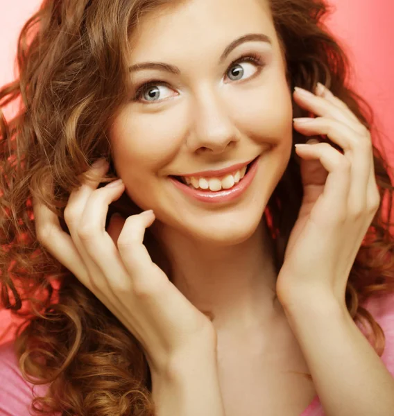 Young beautiful woman with curly hair over pink background — Stock Photo, Image