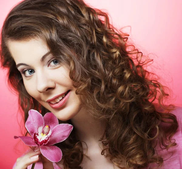 Hermosa mujer feliz con flor de orquídea sobre fondo rosa —  Fotos de Stock