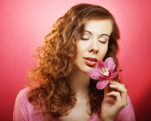 Όμορφη ευτυχισμένη γυναίκα με ορχιδέα λουλούδι πάνω από ροζ φόντο — Φωτογραφία Αρχείου