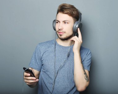 Cep telefonu ve lictening müzik için gri arka plan üzerinde tutan adam