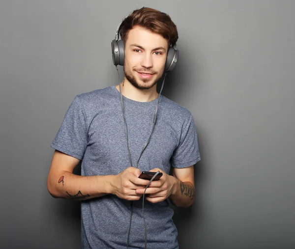 Junger Mann mit Kopfhörer und Handy in der Hand — Stockfoto