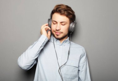 Kulaklık takıp müzik dinleyen yakışıklı bir genç..