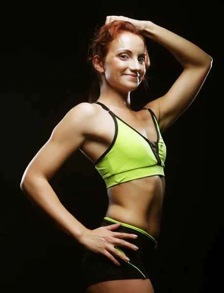 Junge fitnessfrau mit schwarzem hintergrund, sportkonzept — Stockfoto