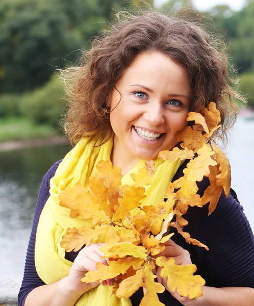 Giovane donna con foglie autunnali nel parco — Foto Stock